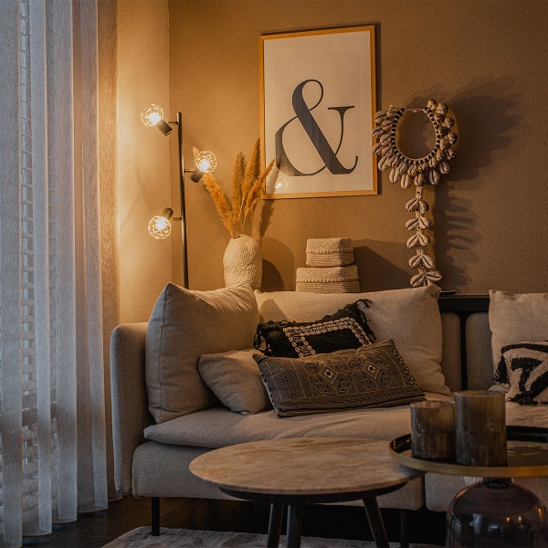 Dekoratives Wohnzimmer mit Sofa, Stehlampe und Wanddekoration