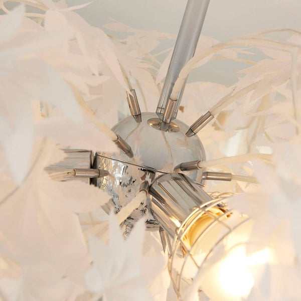 Detailaufnahme einer Deckenleuchte mit verchromter Kugelmitte und weißen Blattornamenten.