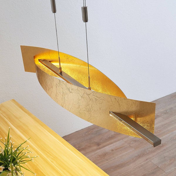 Moderne Pendelleuchte mit gebogenem Schirm in Blattgold-Optik, hängend über einem Holztisch.