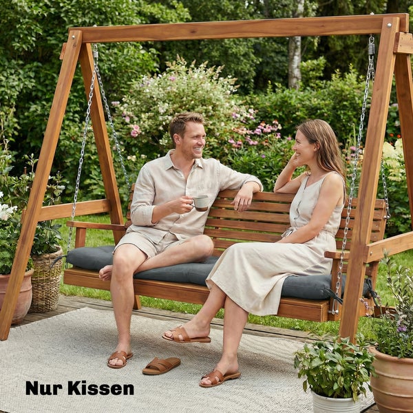 Dunkelgraue Sitzkissen auf einer hölzernen Hollywoodschaukel in einem hellen Garten mit einem Paar.