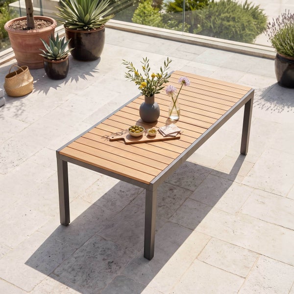 Moderner Gartentisch mit Holzlamellen und dunklem Metallgestell auf einer hellen Terrasse an einem Pool.