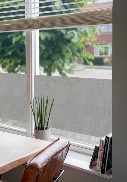 Sichtschutzfolie mit Leinenstruktur auf einer Fensterscheibe in einem hellen Raum mit Zimmerpflanze und Kochbüchern auf der Fensterbank.