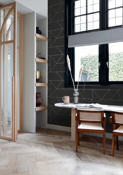 Wohnraum mit Esstisch, Stühlen und Regal an einer Wand mit geometrischer Tapete