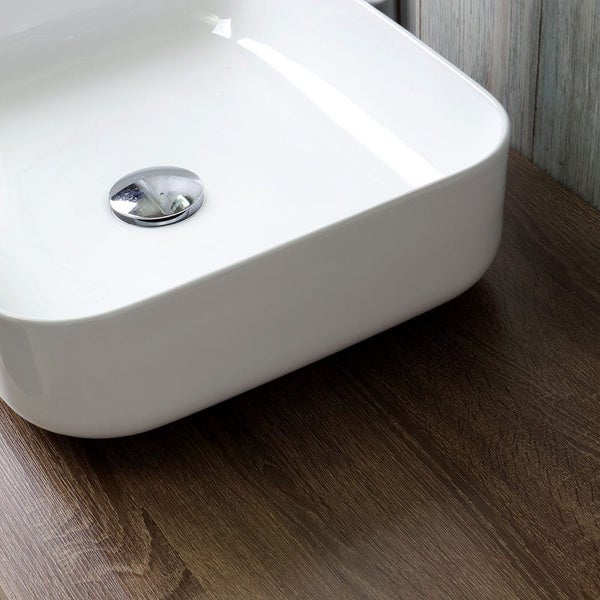 Aufbauwaschbecken aus Sanitärkeramik mit Ablaufgarnitur auf einer Holzoberfläche