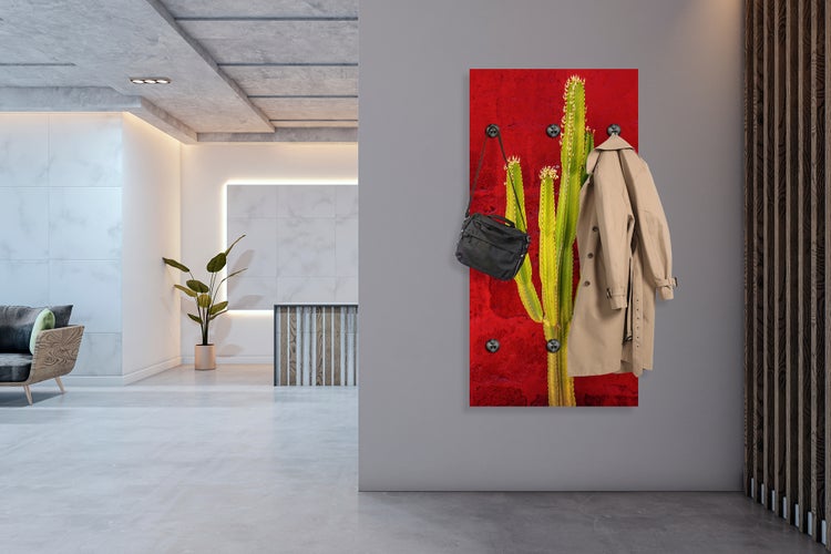 Wandgarderobe mit Kaktusmotiv, einer Tasche und einem Mantel in einem hellen Raum.