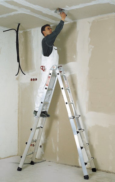 Mann auf einer Aluminium-Leiter, der eine Decke verspachtelt