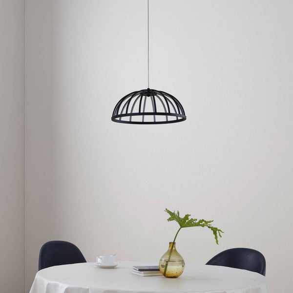 Moderne Pendelleuchte aus schwarzem Metall in Käfigform über einem runden Tisch mit weißer Tischdecke und Stühlen.