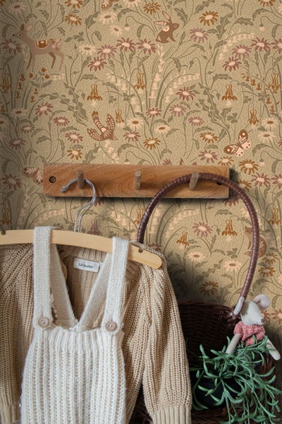 Vliestapete mit Naturmuster aus Waldtieren und Blumen in einem Kinderzimmer mit Kleiderleiste aus Holz und Strickkleidung.