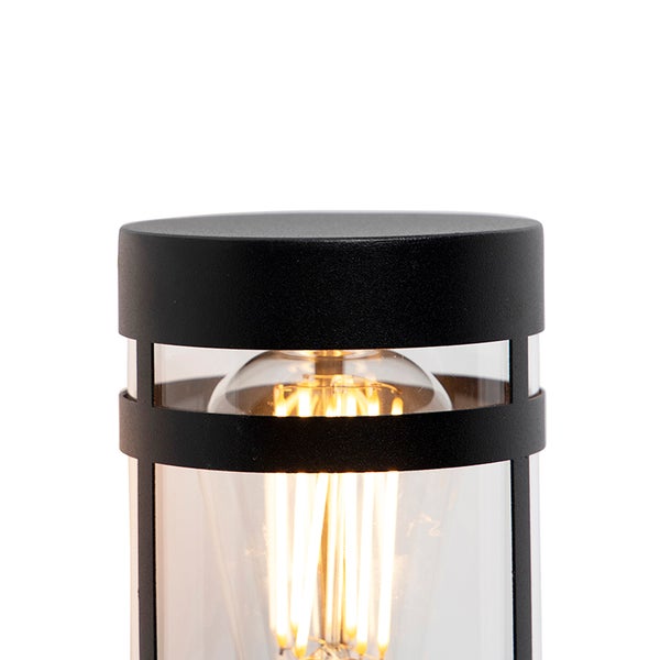 Schwarze Außenstandleuchte aus Metall mit klarem Glaseinsatz und leuchtendem LED-Filament-Leuchtmittel.