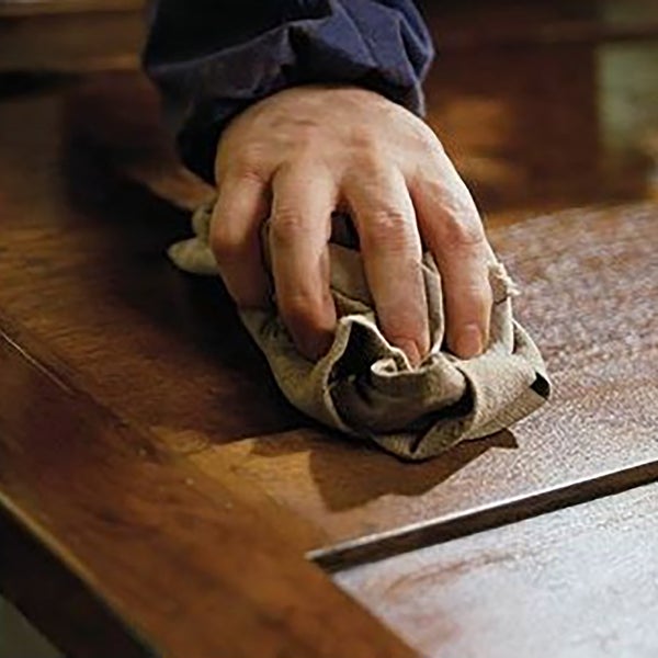 Hand reinigt Holzoberfläche mit Stofflappen