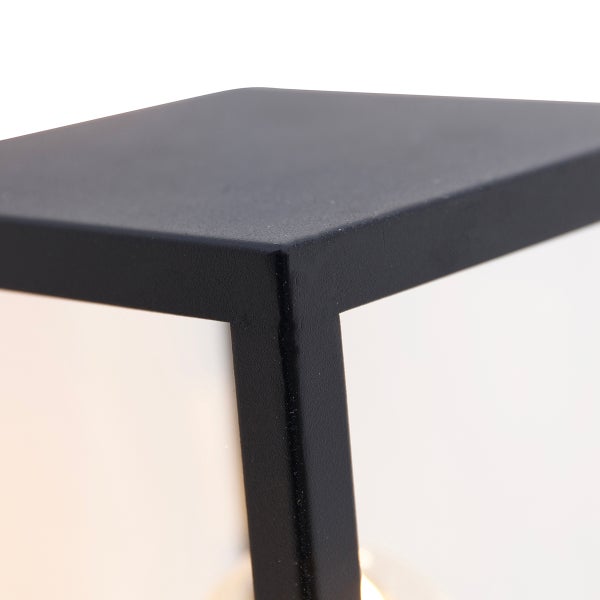 Detailaufnahme der Ecke einer schwarzen Außenleuchte aus Metall mit Glaseinsatz.