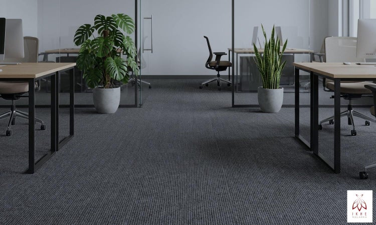 Innenraum mit grauem Teppichboden, Bürotischen und Pflanzen