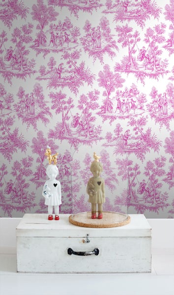 Vliestapete mit Toile-de-Jouy-Landschaftsmuster hinter einer Holzkiste mit Mädchenfiguren in einem hellen Raum.