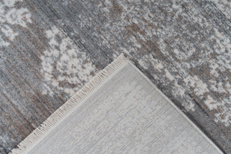 Nahaufnahme eines Vintage-Teppichs mit abstraktem Muster, umgeschlagene Ecke zeigt die gewebte Rückseite und Fransen.