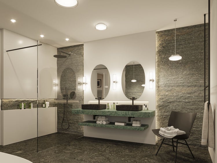 Modernes Badezimmer mit Doppelwaschtisch, grüner Marmorplatte, schwarzen Aufsatzbecken, ovalen Spiegeln, begehbarer Dusche und Steinwand.