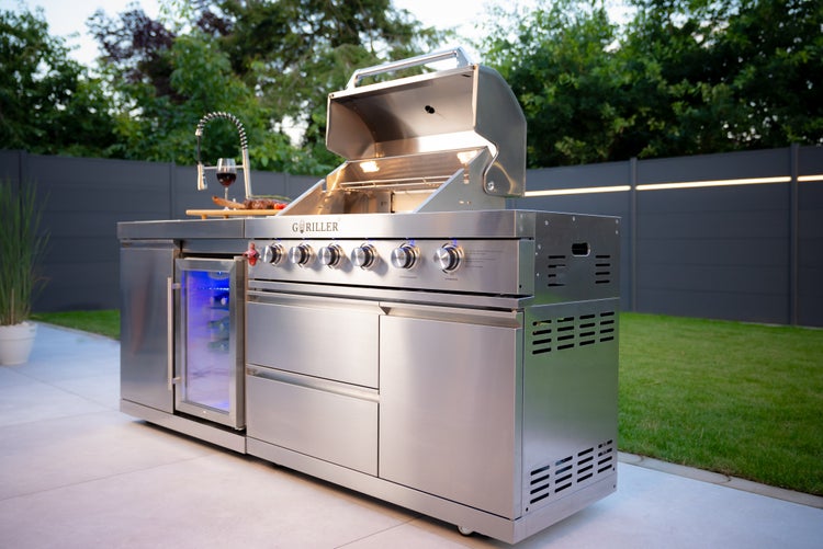 Moderne Außenküche aus Edelstahl mit Gasgrill, Kühlschrank und Spülbecken der Marke Goriller im Garten auf einer hellen Terrasse.