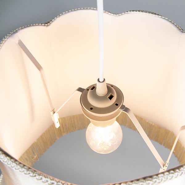 Innenansicht einer Pendelleuchte mit Stoffschirm, Fransenborte und eingeschaltetem Leuchtmittel.