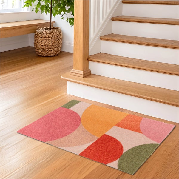 Moderner geometrischer Teppich mit Kreismuster auf Holzboden vor einer Treppe in einem hellen und organisierten Eingangsbereich.