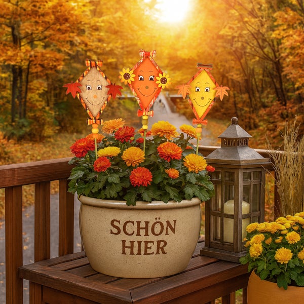Herbstliche Gartendekoration mit Chrysanthemen, Laterne und freundlichen Vogelscheuchenfiguren