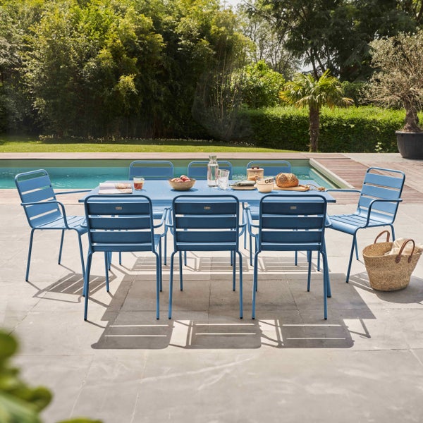 Gartenmöbel Set aus hellblauem Metall bestehend aus einem großen Tisch und acht Stühlen auf einer Terrasse neben einem Pool.