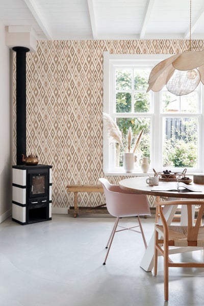 Wohnraum mit gemusterter Tapete, Ofen und Esstisch.