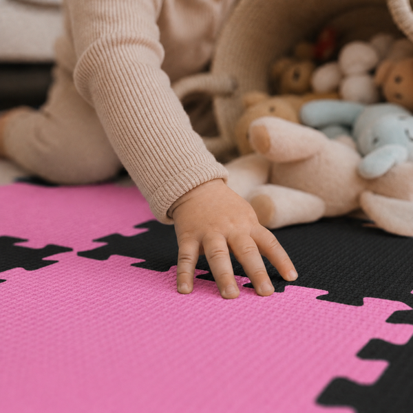 Ein Kleinkind spielt auf einer weichen Schaumstoffpuzzlematte mit Spielzeug.
