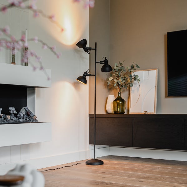 Schwarze Stehlampe mit drei Strahlern in einem Wohnzimmer