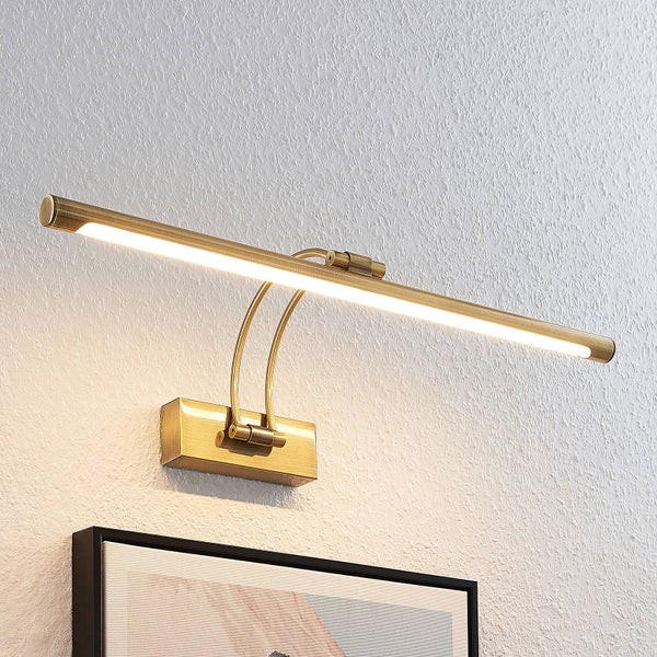 Moderne LED-Bilderleuchte aus Messing mit schlankem Design, verstellbar, an einer Wand über einem Bilderrahmen montiert, hell leuchtend.