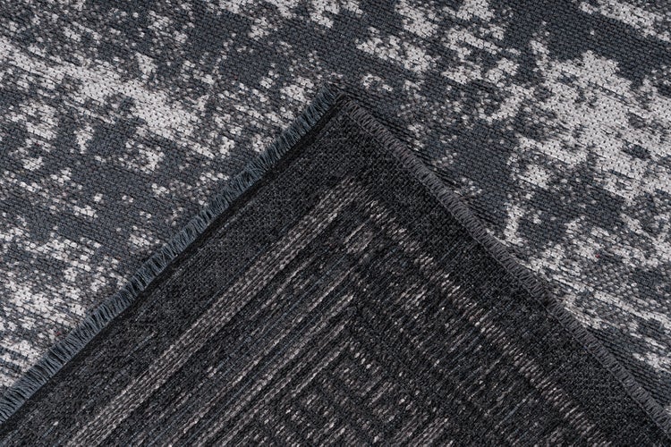 Nahaufnahme eines flachgewebten Teppichs mit Vintage-Muster in Anthrazit und Grau, Rückseite sichtbar.