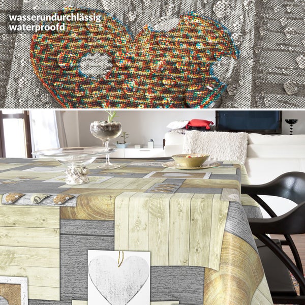 Wasserundurchlässige Tischdecke mit Holz- und Herz-Patchwork-Muster, auf einem Tisch in einem hellen Wohnzimmer sowie Detailansicht mit Wassertropfen.
