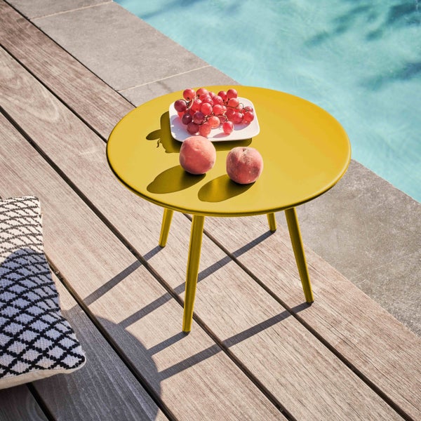 Runder gelber Beistelltisch auf einer Holzterrasse am Pool, dekoriert mit Weintrauben und Pfirsichen.