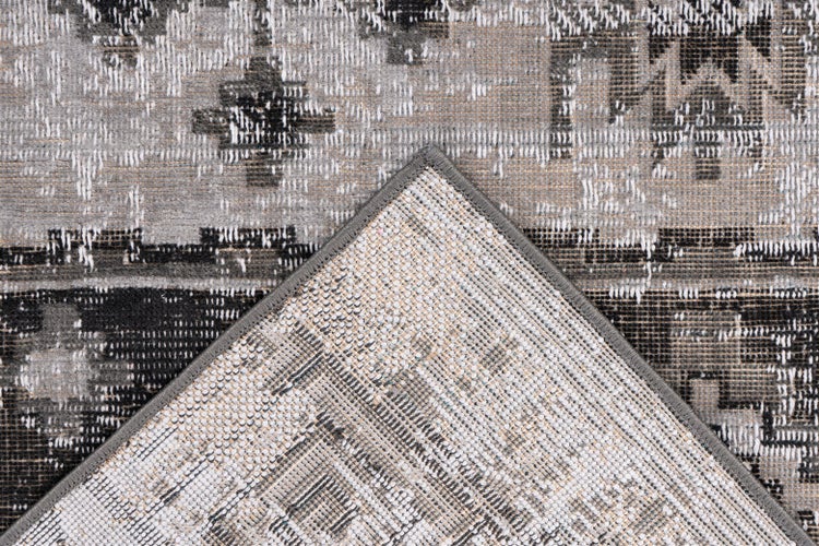 Nahaufnahme eines Teppichs mit Vintage-Muster und umgeknickter Ecke, die die gewebte Rückseite zeigt.