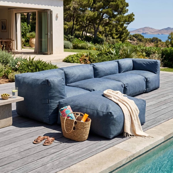 Modulares Lounge-Gartensofa und Hocker auf einer Holzterrasse am Pool, moderner Stil in Blau, helle und weitläufige Gestaltung mit Gartenblick.