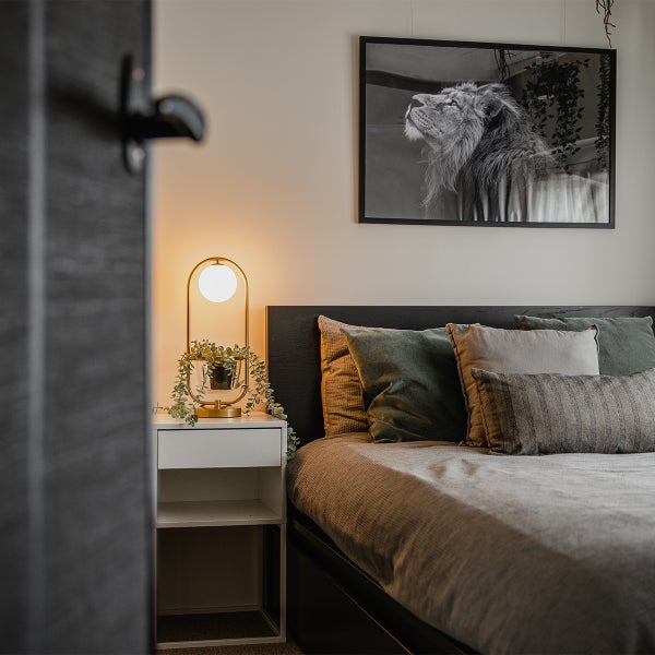 Schlafzimmer mit Bett, Nachttisch, Lampe und Schwarzweißbild an der Wand