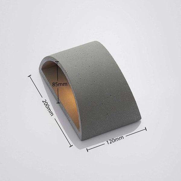Graue Wandleuchte aus Beton in gebogener Form, Maße 200 Millimeter mal 120 Millimeter mal 85 Millimeter.