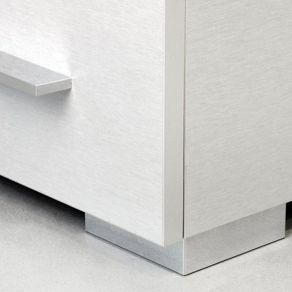 Detailansicht eines Badezimmermöbels mit Front in Holzoptik und glänzenden Metallfüßen und Griffleiste.