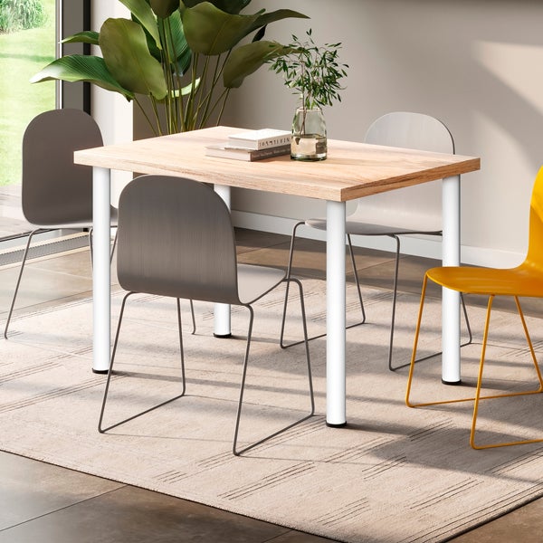 Moderner Esstisch mit Holzplatte und weißen Tischbeinen in einem hellen, wohnlich eingerichteten Esszimmer mit verschiedenen Stühlen.