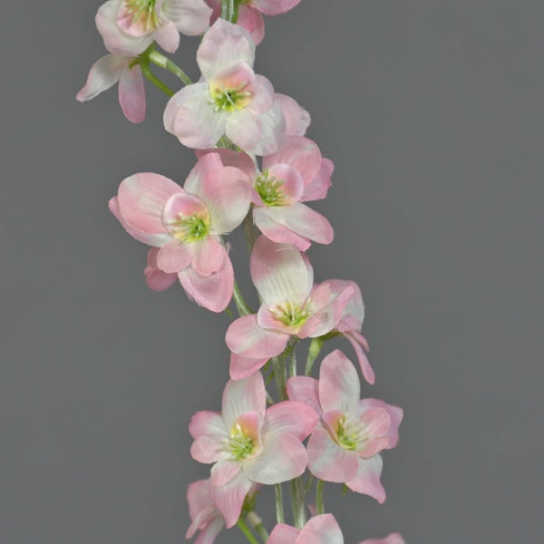 Künstlicher Blütenzweig mit rosa und weißen Textilblüten.