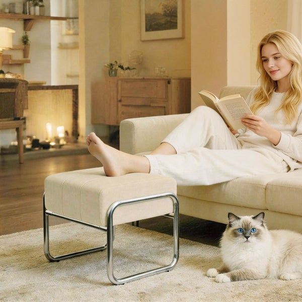 Wohnzimmer mit Frau, die auf einem Sofa liest, und einem Hocker mit Metallbeinen