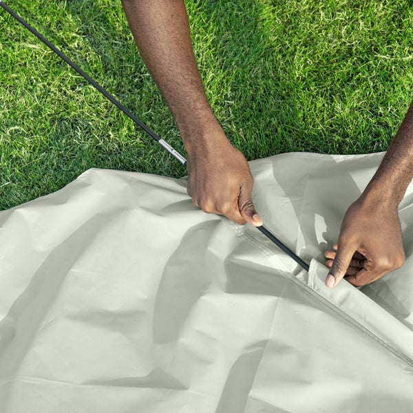 Person steckt Zeltstange in ein Zelt auf einer Wiese