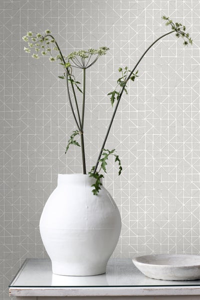 Dekorative Wandgestaltung mit geometrischem Fliesenmuster und Blumenvase