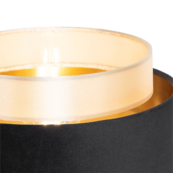 Nahaufnahme eines zylindrischen Doppellampenschirms mit schwarzer Textil-Außenschicht, goldfarbener Innenbeschichtung und lichtdurchlässigem Innenschirm.