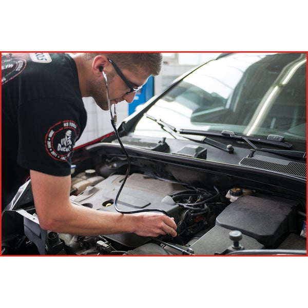 Ein Mechaniker verwendet ein Stethoskop zur Diagnose eines Automotors.