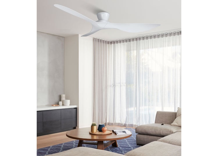 Moderner Deckenventilator mit drei geschwungenen Rotorblättern installiert in einem hellen und stilvoll eingerichteten Wohnzimmer.