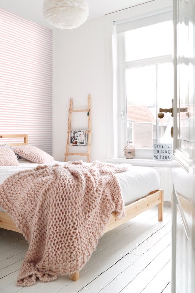 Helles Schlafzimmer mit Holzbett und Strickdecke