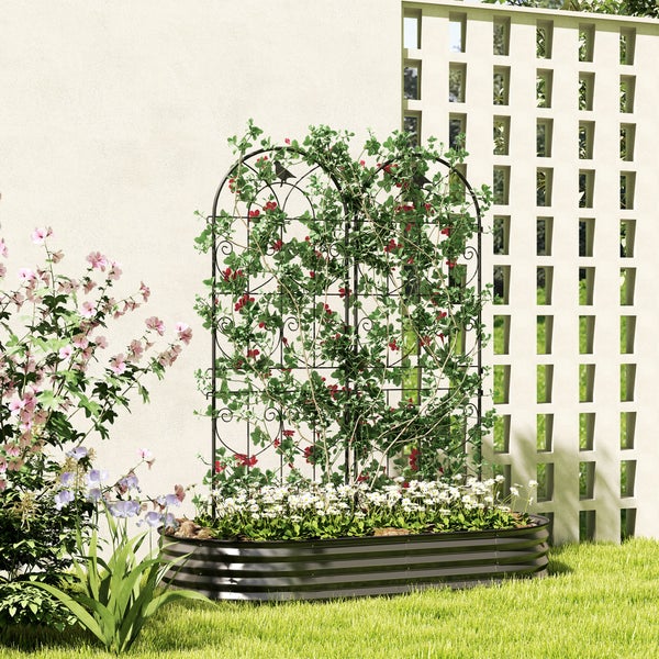 Dunkles Hochbeet aus gewelltem Metall mit bogenförmiger Rankhilfe, bepflanzt mit Kletterpflanzen und Blumen in einem hellen Garten.