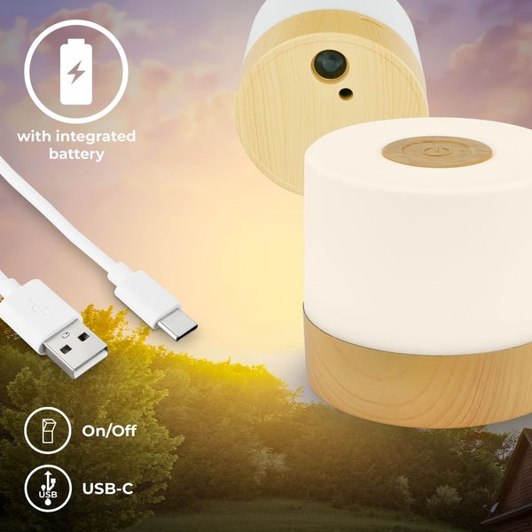 Tragbare LED-Tischleuchte auf einem Holztisch auf einer Terrasse mit Aussicht auf grüne Hügel.