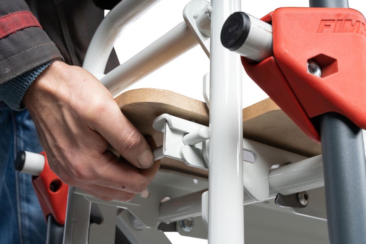 Hand, die eine Holzplatte an einem Metallgerüst befestigt, Teil einer Bauanleitung.