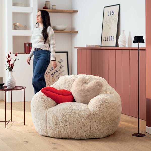 Wohnzimmer mit Deckenleuchten, Sessel und Sideboard für eine helle und organisierte Atmosphäre