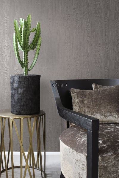 Dekoratives Interieur mit Kaktus in einem Topf auf Beistelltisch, Stuhl mit Kissen vor gemusterter Tapete.